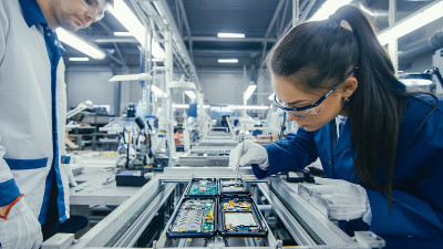 图为电子厂工人在装配线上手工组装电路板。高科技工厂设施。