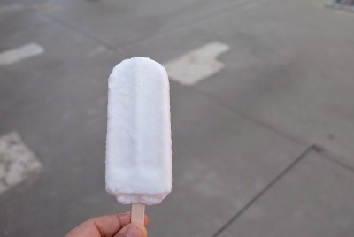 一个男人的手拿着一个融化的椰奶冰淇淋的木棒