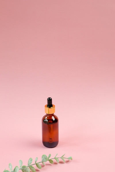 琥珀色的玻璃瓶CBD油在粉红色的背景与复制空间