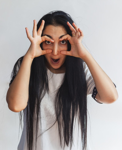 一个可爱女人的滑稽肖像。万圣节的女人。女人想睁大眼睛。女性做滑稽的面部表情。一个快乐顽皮的黑发女孩的