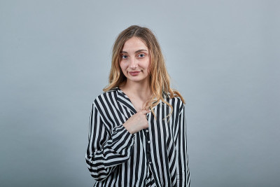穿着条纹衬衫的快乐女人指着自己，微笑着