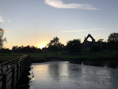 英国，北约克郡，约克郡谷地，从横跨沃夫河的人行桥上俯瞰修道院剪影