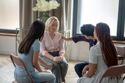 一个金发女人坐在朋友圈里讲述她的故事，看起来很沮丧