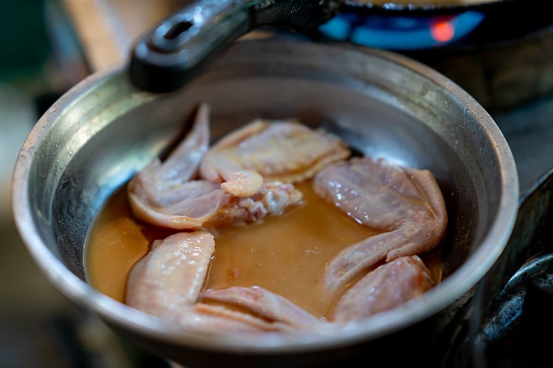 鸡肉放在热油锅里煮菜单，合上鸡腿和鸡翅，油泡和飞溅，在炉子上的肥油中炒烤