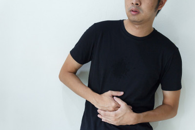 一个年轻的亚洲男人正在胃痛。
