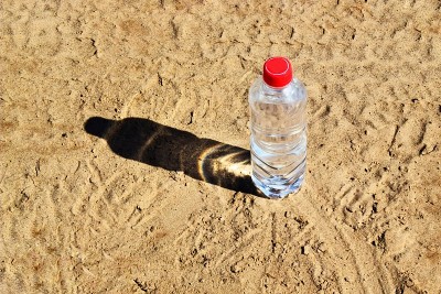 沙滩上的水瓶。在炎热的夏天口渴晴天近距离