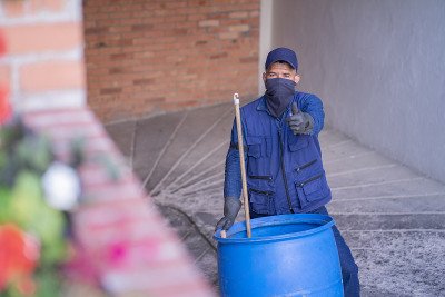 一名拉丁裔男子是建筑清洁工，他拿着垃圾桶爬上了停车场的坡道，一边看着摄像头，一边竖起大拇指