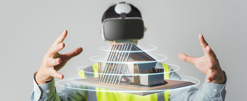 建筑师或工程师使用VR耳机为BIM技术工作设计三维房屋模型在建筑完成。