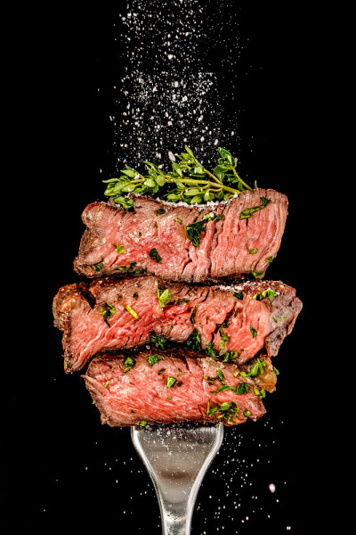 用叉子烤好的切片牛肉。盐从上面撒下来