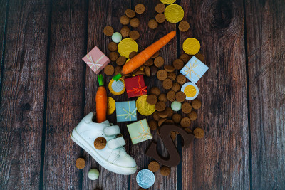 荷兰节日的Sinterklaas背景有儿童鞋、胡萝卜为圣诞老人的马、礼物、传统的蜜饯和巧克力信。平铺