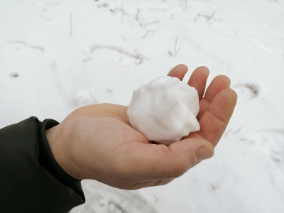 一个男人手里的雪球。一个人手里捏成的雪球。