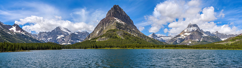 春天在Swiftcurrent湖- Swiftcurrent湖全景，崎岖的山峰高耸在西海岸，在一个阳
