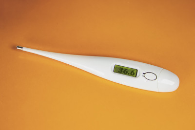 电子温度计在橙色背景平铺俯视图拷贝空间。预防病毒、冠状病毒、流感、感冒、疾病。医疗工具，健康理念。过