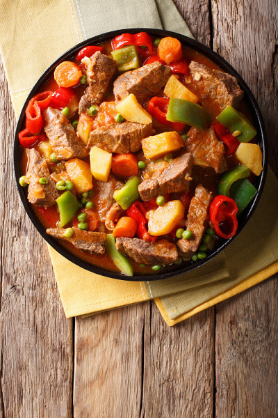 亚洲食物:用土豆、辣椒、豌豆、西红柿和胡萝卜炖牛肉。垂直的俯视图