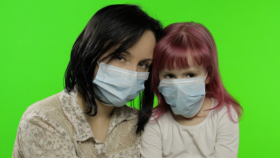生病的母亲抱着带医用口罩的女儿。冠状病毒的概念。家庭隔离