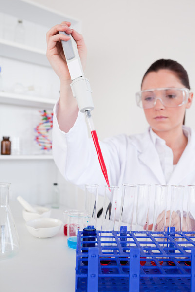 漂亮的女性生物学家拿着手动吸管和试管样本