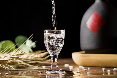 中国白酒，烈酒饮料从一个瓶子倒进一个玻璃杯的木材背景