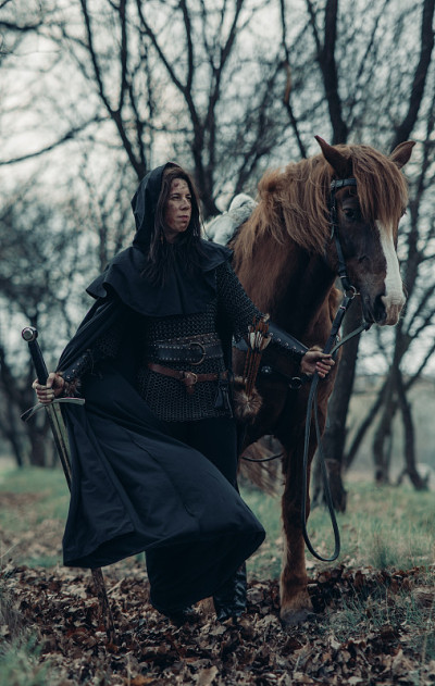 中世纪武士形象中的女子手持长剑牵着她的马。