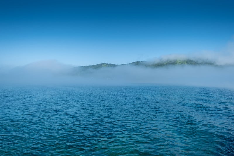 贝加尔湖附近的村庄，贝加尔港，俄罗斯。晴天的高海岸和清澈的湖水与雾