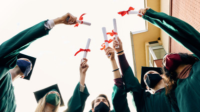 在新冠肺炎大流行期间，快乐的大学生庆祝毕业。