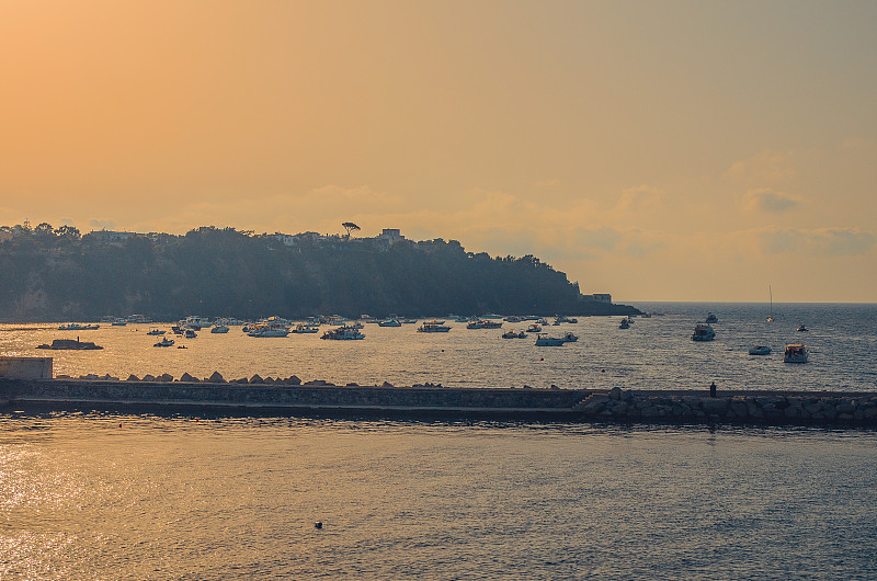 日落时分，意大利那不勒斯海岸附近地中海普罗西达岛附近的海湾里的小船