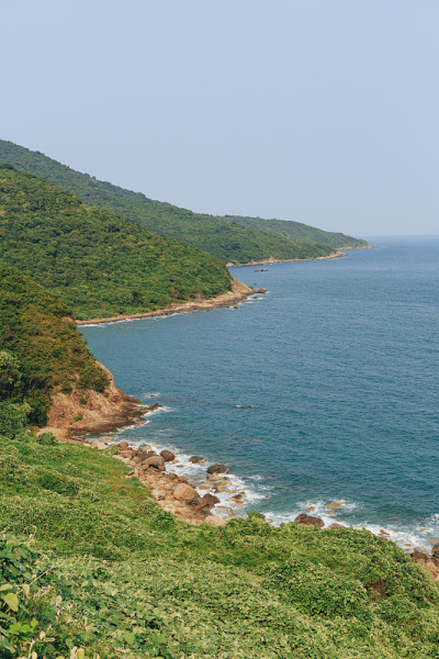 越南岘港海凡山口顺化的琅哥海滩全景。火车在海边的铁路上行驶，绿色的森林，美丽的自然景观，海浪