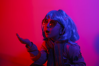 小女孩戴着彩色假发和心形太阳镜摆姿势拍飞吻照