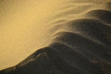 新西兰海滩上的金色沙滩上海浪形成的抽象图案;清晨——美丽的阳光。的背景图片。