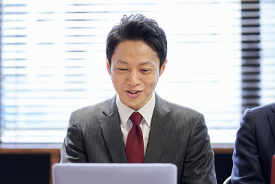 一位亚洲商人面带微笑在电脑前工作