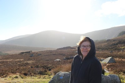 Senior female tourist poses on top of the Wicklow 