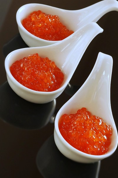 红色鱼子酱在小碗玻璃黑色的背景。俯视图