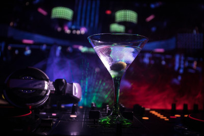 在夜总会的dj控制器上放着杯里有橄榄的马提尼酒。Dj控制台与俱乐部饮料在音乐派对在夜总会迪斯科灯。关