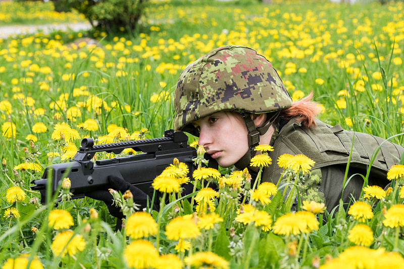 身着迷彩服的武装女子的肖像。年轻的女兵用枪观察。