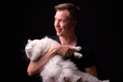 在黑色背景下，人抱着猫的工作室肖像