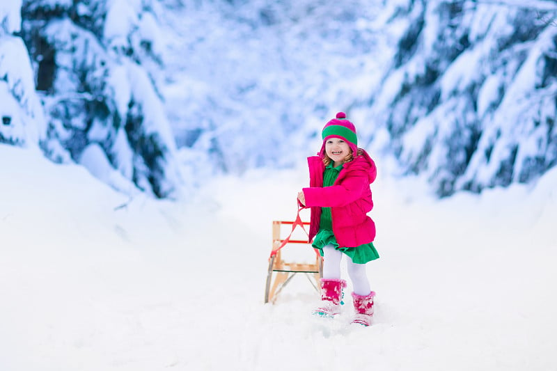 小女孩在下雪的冬天公园玩