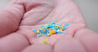 一个人的侧面持有微塑料在他的手。再利用的材料。选择性聚焦与浅景深的领域。