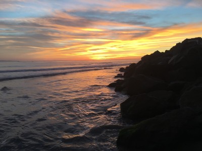 海滩岩石旁明亮的夕阳
