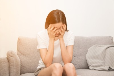 患有严重偏头痛的亚洲妇女双手抱头。