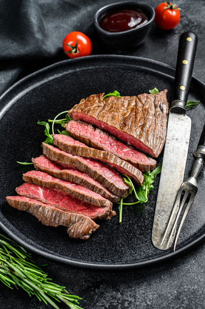 烤和切平铁牛排。大理石牛肉肉。黑色背景。俯视图