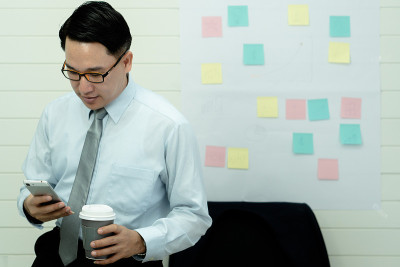 专业的商务人士手持在纸杯玻璃杯中喝新鲜的咖啡早上清爽的咖啡休息前工作会议电脑智能手机手机