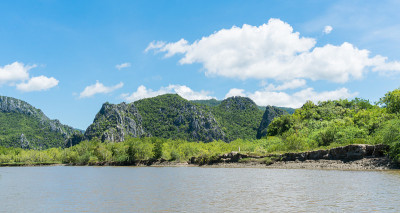 石头或岩石山或小山，绿树、蓝天、水和云