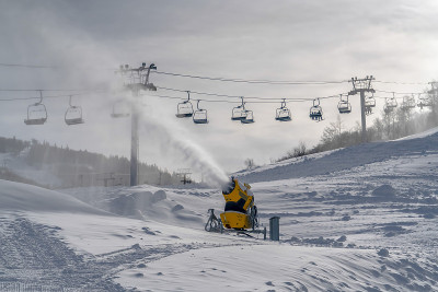 阳光明媚的山坡上有雪炮和滑雪缆车