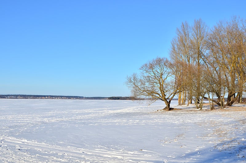 在蓝色的天空背景上结冰的湖的冬季场景。雪河视图