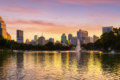 泰国曼谷，市中心公园的自然湖，有商业建筑和日落天空的背景