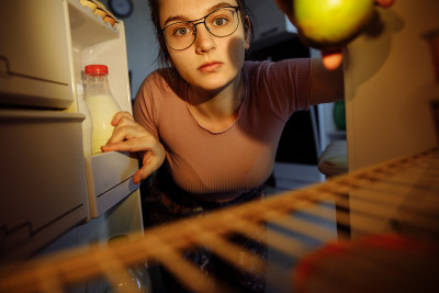 晚上，这个女孩把手伸进冰箱里拿食物