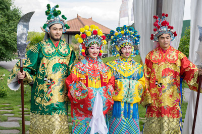 四名亚洲男女穿着中国传统服装，站成一排，在户外打招呼