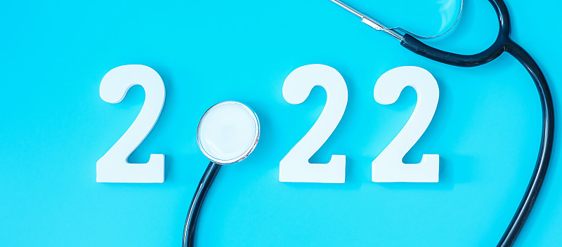 2022年健康、保险、健康、医疗理念新年快乐。听诊器和蓝色背景上的白色数字