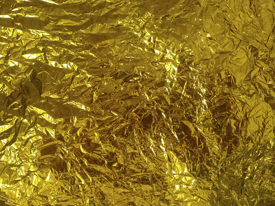 一张金色的纸。闪闪发光的金箔纹理背景。有皱纹和褶皱的黄色包装纸图案。富有活力的装饰纹理