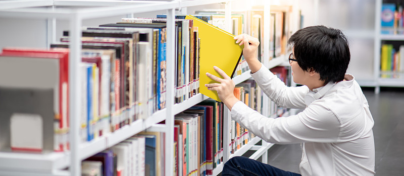 亚洲曼大学生在图书馆选书