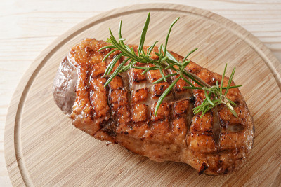 香脆的烤鸭胸肉配上迷迭香装饰在木砧板上，从高处俯瞰